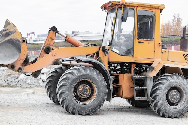 Der Lader transportiert in der Frontschaufel Sand oder Kies Schweres Baugerät auf einer Baustelle Transport von Schüttgütern in einem Betonwerk