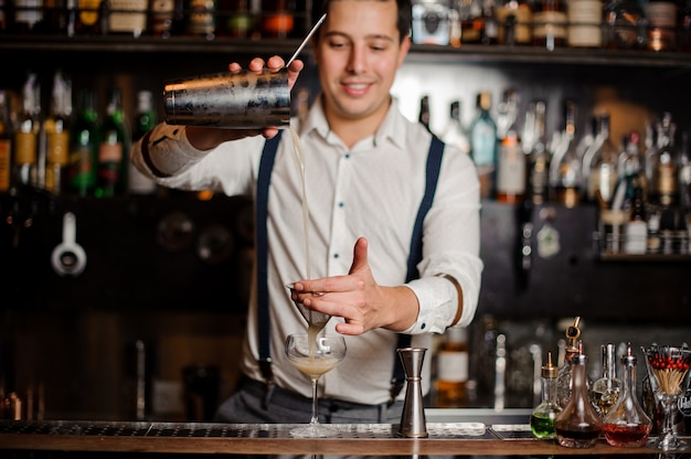 Der lächelnde Barkeeper macht an der Bar einen Cocktail