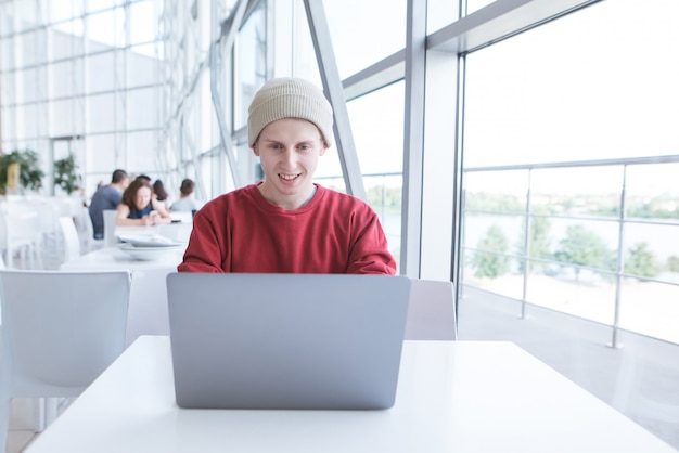 Der lächelnde junge Freiberufler arbeitet mit einem Laptop