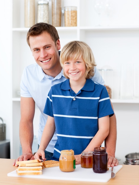 Der lächelnde Vater, der seinem Sohn hilft, bereiten das Frühstück vor