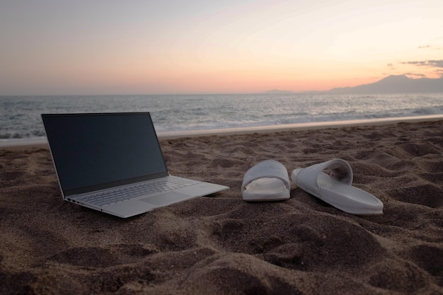 Der Laptop liegt auf dem Sand am Strand. Das Konzept, überall online zu arbeiten.