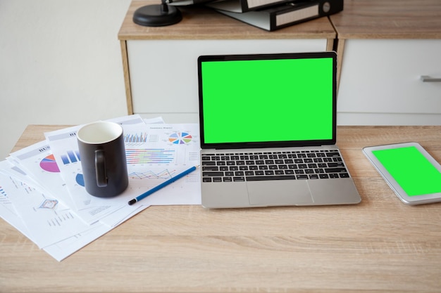 Der Laptop liegt mit vielen Dokumenten auf dem Schreibtisch