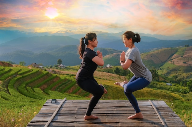 Der Lebensstil einer Frau, die abends auf einer Brücke inmitten der Bergnatur Meditation und Zen-Energie-Yoga im Freien praktiziert. Mit Sonnenuntergang