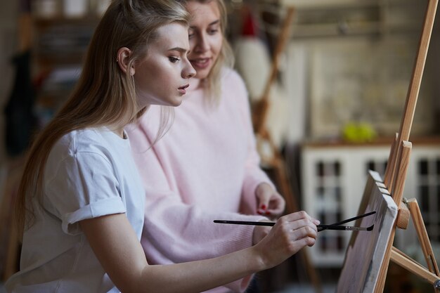 Der Lehrer bringt einem jungen Mädchen bei, auf Leinwand zu malen