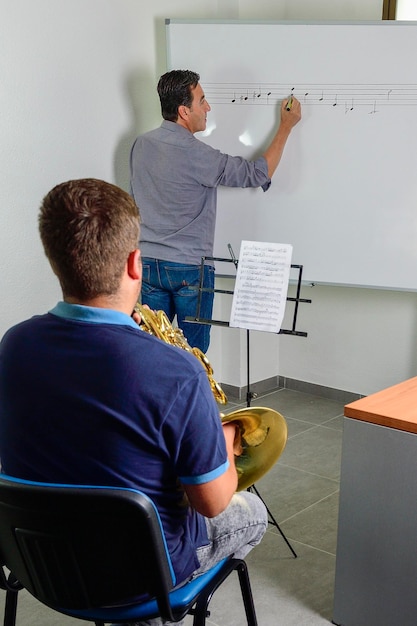 Der Lehrer korrigiert Musik im Klassenzimmer für einen jungen Schüler