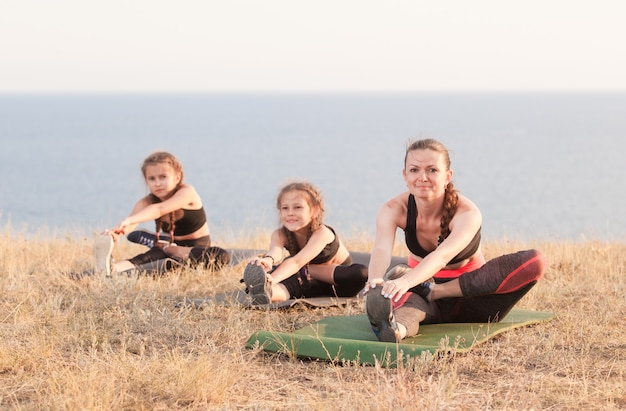 Der Lehrer trainiert Yoga-Kinder in den Bergen am Meer.