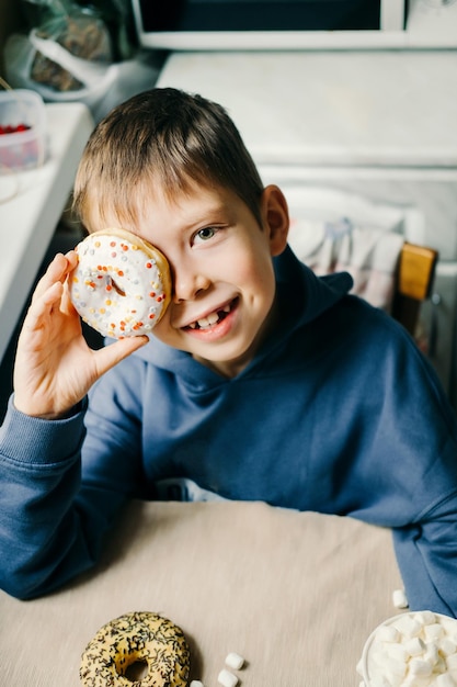 Der lustige Junge mit dem Donut-Kind amüsiert sich mit den Donuts, einem leckeren Essen für Kinder.