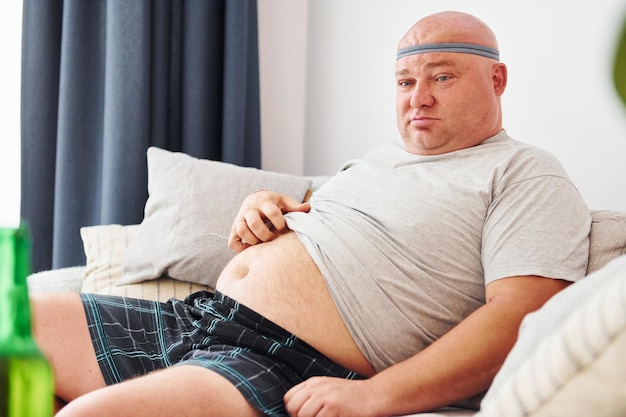 Der lustige übergewichtige Mann in Freizeitkleidung ist zu Hause