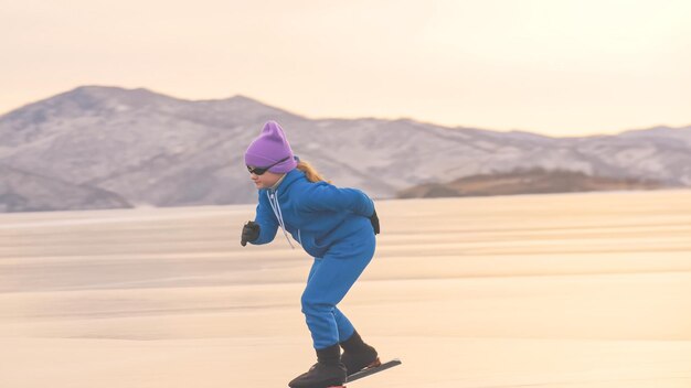 Der Mädchenzug auf Eisschnelllauf. Das Kind skatet im Winter in blauem Sportanzug, Sportbrille. Eisschnelllauf für Kinder.