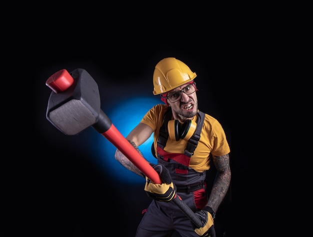 Der männliche Bauarbeiter mit einem Vorschlaghammer