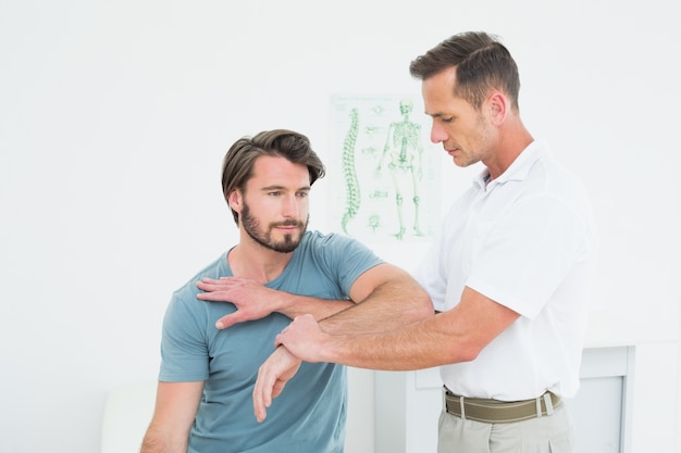Der männliche Physiotherapeut, der ein Junges ausdehnt, bemannt Hand
