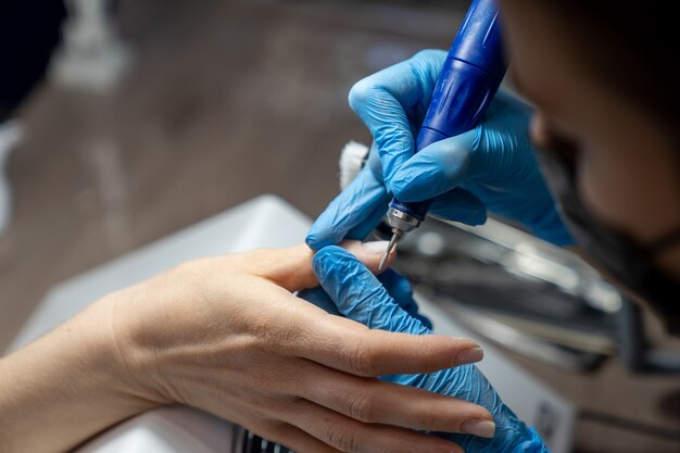 Der Manikürist behandelt die Finger des Kunden mit einer speziellen Düse zur Lederbehandlung