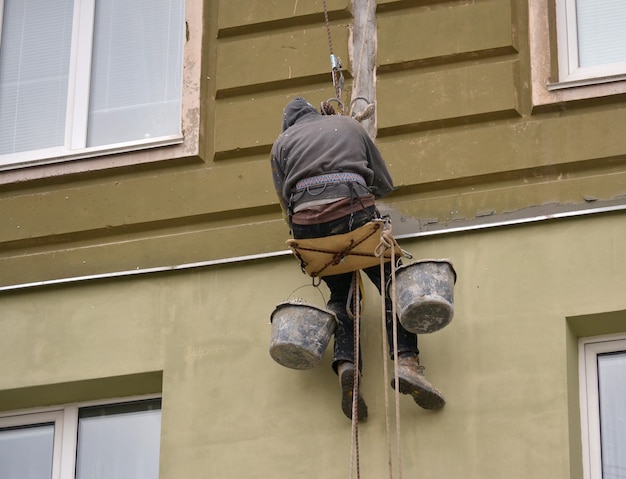 Der Mann arbeitet an Hochhausarbeiten Verputzen des Hauses