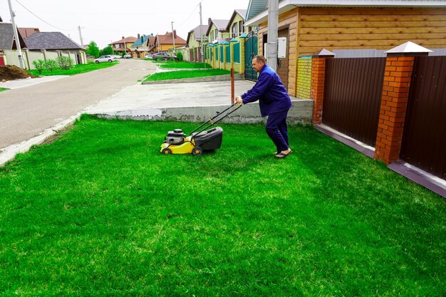 Der Mann arbeitet im Garten und mäht Gras mit einem Rasenmäher