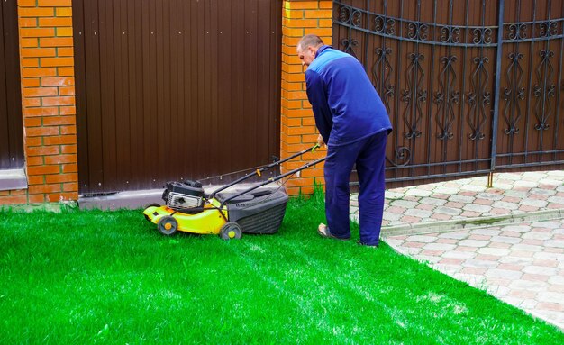 Der Mann arbeitet im Garten und mäht Gras mit einem Rasenmäher