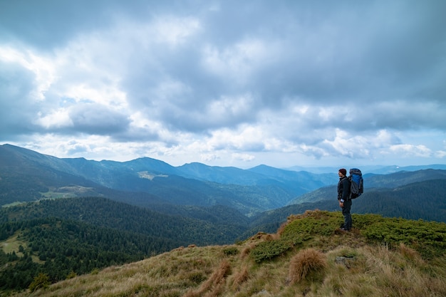 Der Mann, der auf dem Berg auf dem Wolkenhintergrund steht