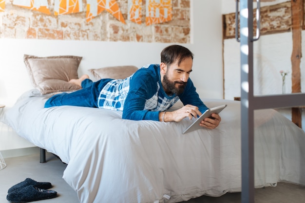 Der Mann, der im Bett sitzt, entspannte sich zu Hause auf dem Tisch