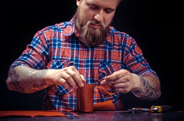 Der Mann, der mit Leder arbeitet, bildet in seiner Werkstatt ein neues Lederprodukt