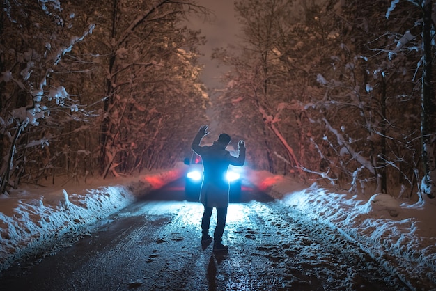 Der Mann erschreckte das Auto auf der verschneiten Straße. abend nacht zeit