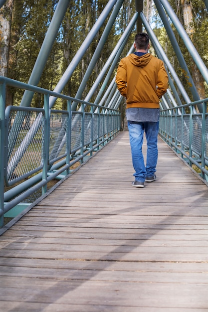 Der Mann geht im Herbst über die Brücke