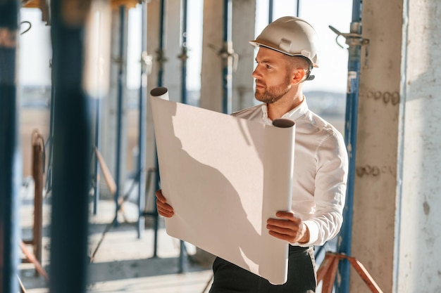 Der Mann hält den Plan in den Händen und arbeitet tagsüber auf der Baustelle