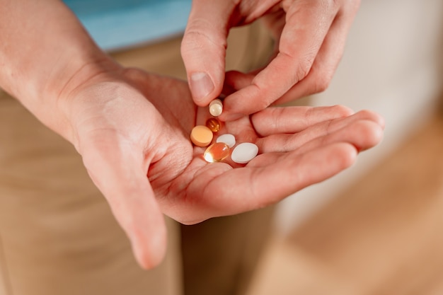 Der Mann hält Pillen und Kapseln in der Hand Einnahme von Vitaminen und Medikamenten aus nächster Nähe