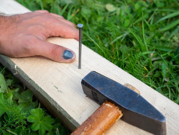 Der Mann hämmerte einen Nagel in das Brett, traf aber auf den Finger seiner Hand Hämatomverletzung Arbeitsunfall Ein Versicherungsfall