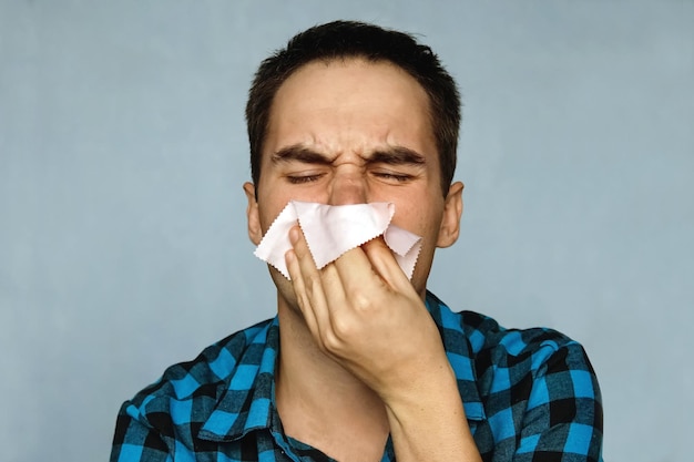Der Mann hat eine laufende Nase. Die Person mit einer Erkältung niest in ein Taschentuch. Rotz kommt aus der Nase