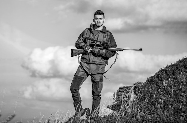 Der mann ist auf der jagd. jagdgewehr jagen. jäger mit jagdgewehr und jagdform, um himmelshintergrund zu jagen. jäger zielt. jäger mann. shooter, der im ziel anvisiert. jagdzeit