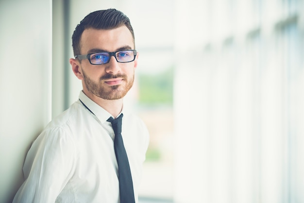 Der Mann mit Brille steht neben der Säule im Büro