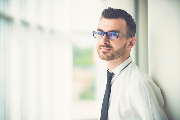 Der Mann mit Brille steht neben der Säule im Büro