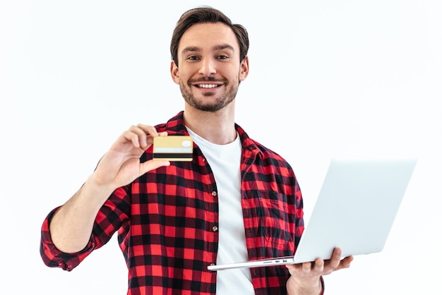 Der Mann mit Kreditkarte und Laptop steht auf weißem Hintergrund