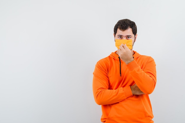 Der Mann mit medizinischer Maske hält sie auf weißem Hintergrund