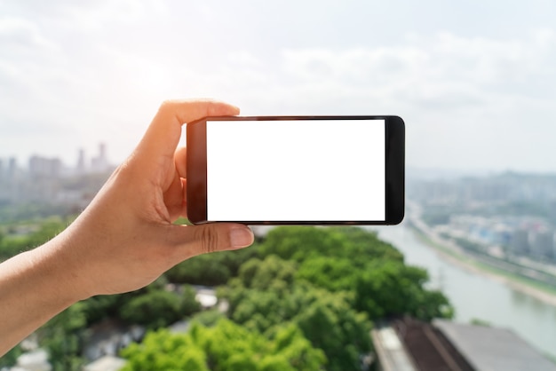 Der Mann nimmt ein Handy, um die Skyline der Stadt zu fotografieren