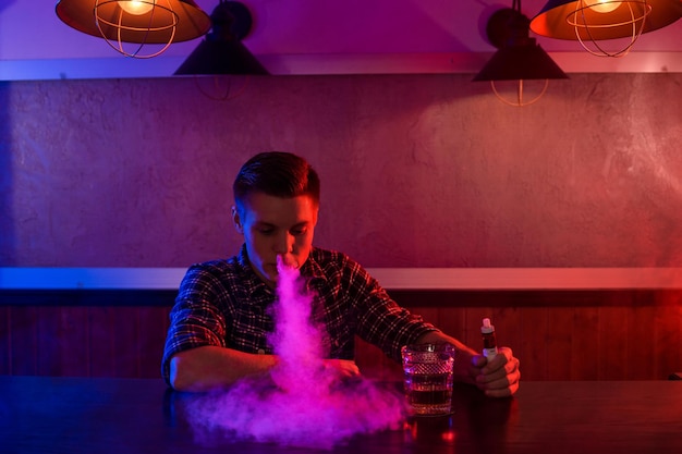 Der Mann raucht im Vape-Shop eine elektronische Zigarette. Vape-Bar.