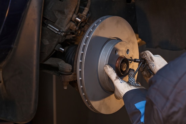 Der Mann repariert die Scheibenbremse im Auto. Scheibenbremse reparieren.