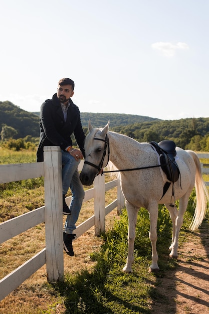 Der Mann ruht sich mit einem Pferd auf einer Ranch aus