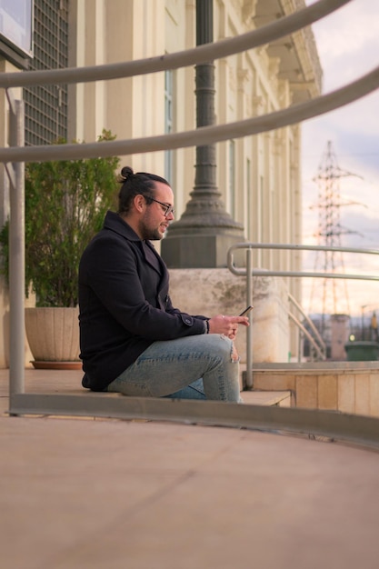 Der Mann schaut auf sein Telefon, das auf der Treppe auf der Straße sitzt