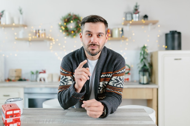 Der Mann selbst zu Hause schaut in die Kamera und kommuniziert per Videolink, Blick aus der Webcam, grüßt Freunde und Kollegen mit Weihnachts- und Neujahrsferien