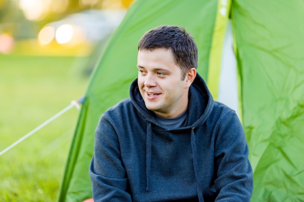 Der Mann sitzt neben dem Zelt auf dem Campingplatz