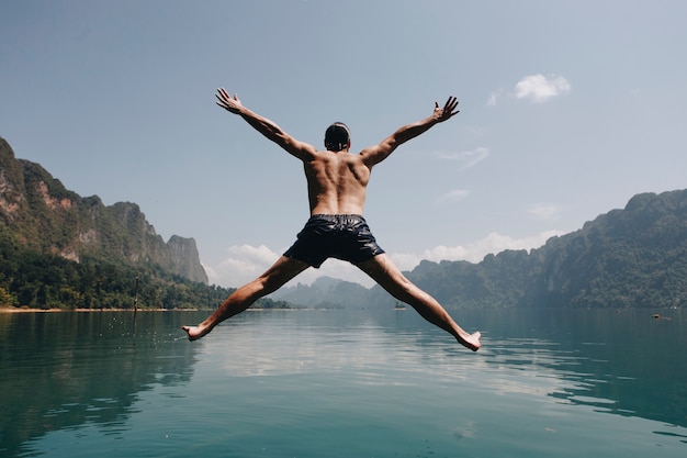 Der Mann springend mit Freude an einem See