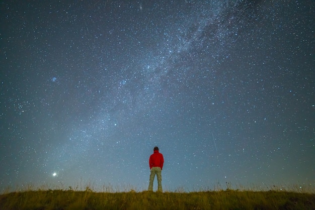 Der Mann steht auf dem Hintergrund der Milchstraße. Nachtzeit