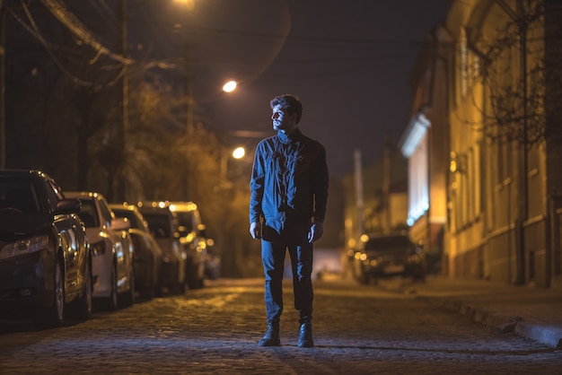 Der Mann steht auf der Straße. Abend Nachtzeit. Aufnahme mit Teleobjektiv