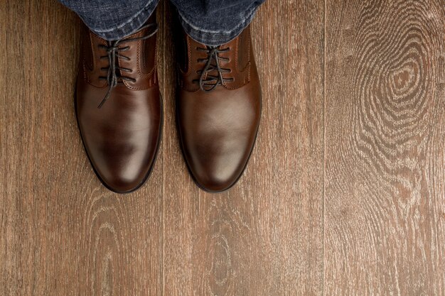 Der Mann trägt braune klassische Schuhe auf Holzmehl.