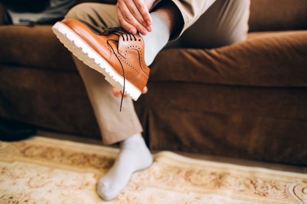 Der Mann trägt Schuhe. Binden Sie die Schnürsenkel an den Schuhen. Männerstil. Berufe. Um sich auf die Arbeit vorzubereiten, zum Treffen.