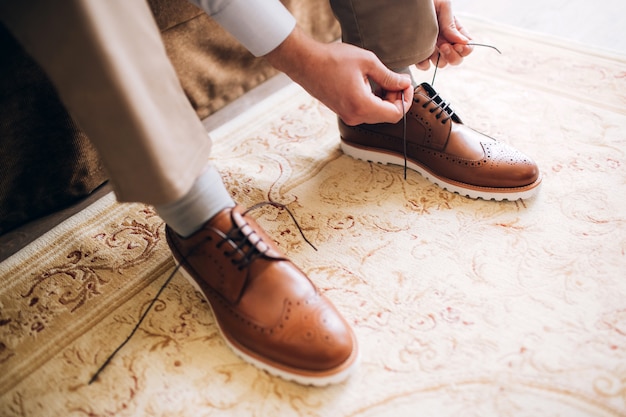 Der Mann trägt Schuhe. Binden Sie die Schnürsenkel an den Schuhen. Männerstil. Berufe. Um sich auf die Arbeit vorzubereiten, zum Treffen.