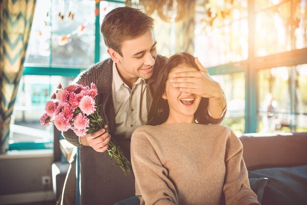 Der Mann überrascht mit Blumen für eine Freundin im Restaurant