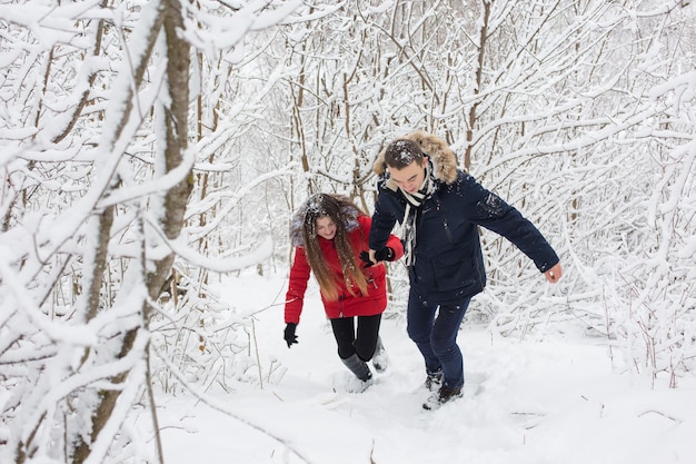 Der Mann und das Mädchen erholen sich im Winterwald Mann und Frau im Schnee Junges Paar zu Fuß im Winterpark