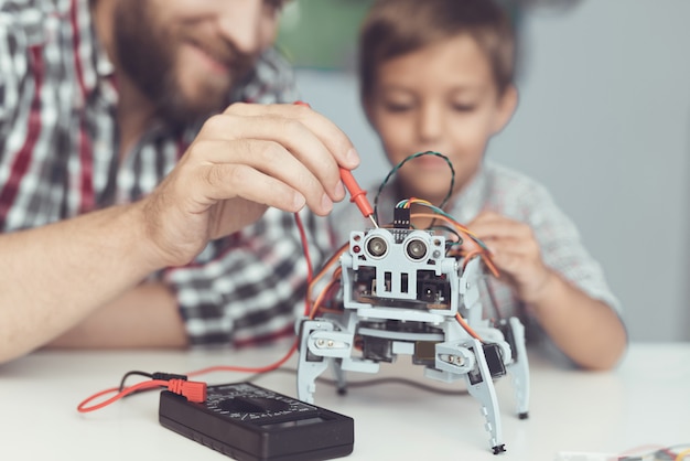 Der Mann und der kleine Junge messen die Leistung des Roboters.