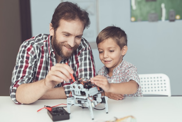 Der Mann und der kleine Junge messen die Leistung des Roboters.
